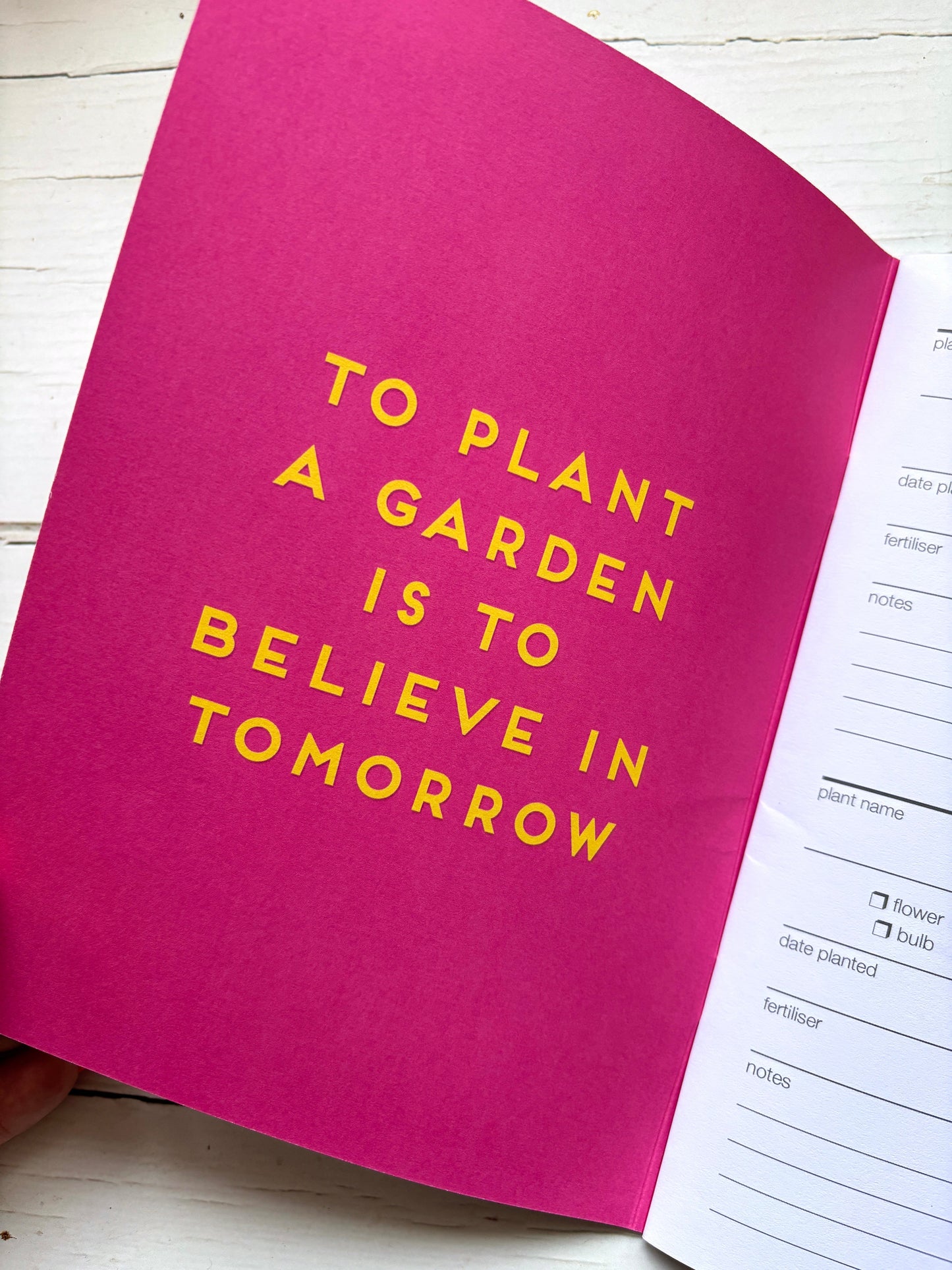 Pink garden journal notebook with yellow text on a white surface