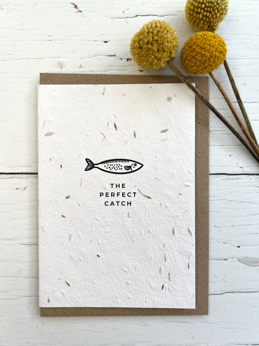 a natural coloured greetings card embedded with meadow seeds and illustrated with a fish and the words "the perfect catch"