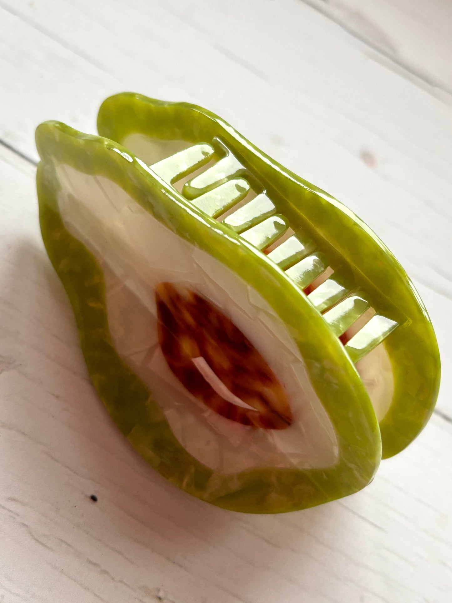 closeup shot of oversized avocado hair claw clip green acetate fruit accessory for thick hair fun, novelty food hair grip