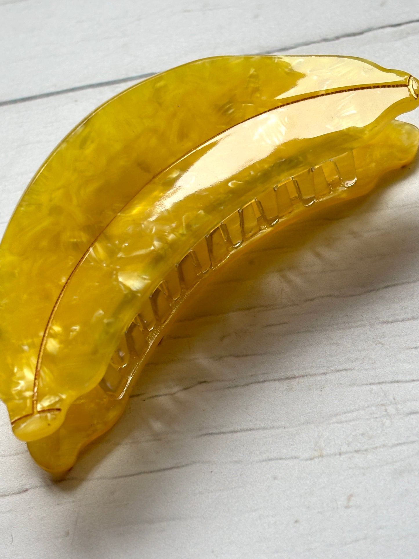 closeup shot of the bright yellow marbled acrylic banana hair claw clip, showing the strong grip teeth mechanism fun hair accessory