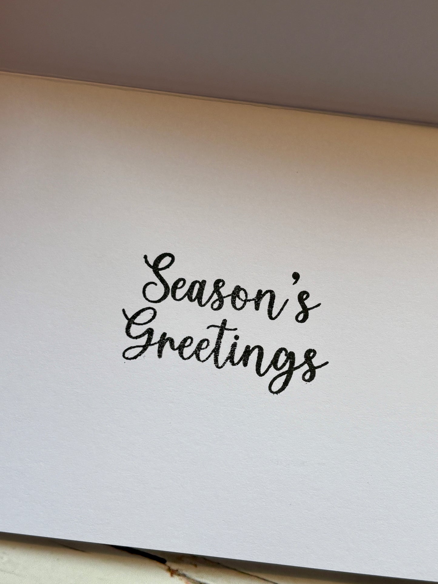 inside of a Christmas card featuring "Season's Greetings" in black script font holiday messages, generic greeting card text