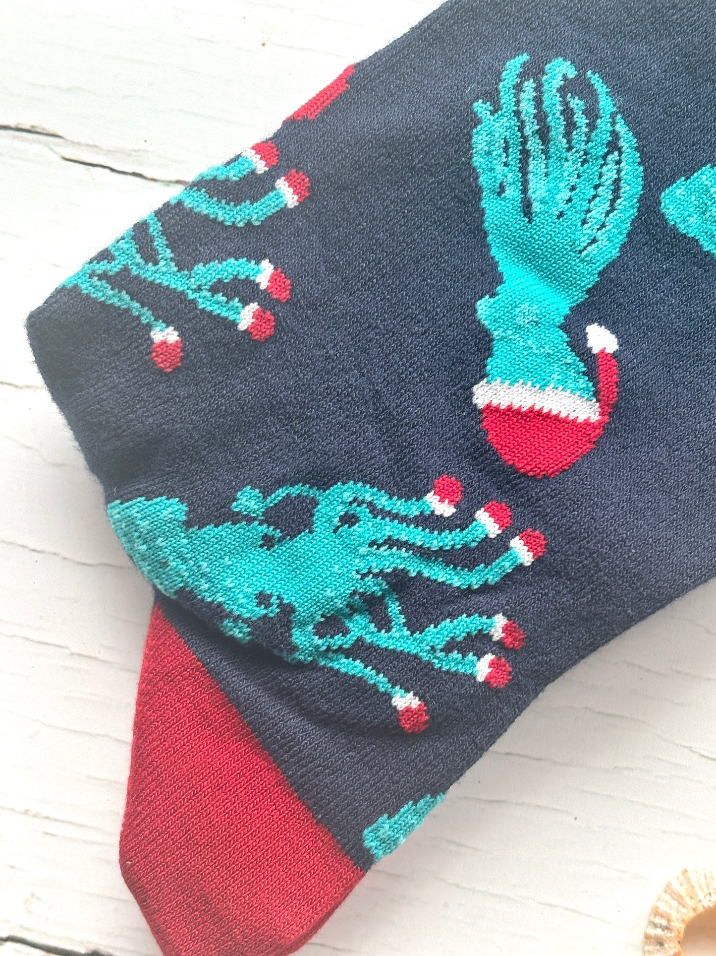closeup shot of teal octopus/squid on navy socks holiday socks detail with red Santa hats and red suction cups festive sea life print