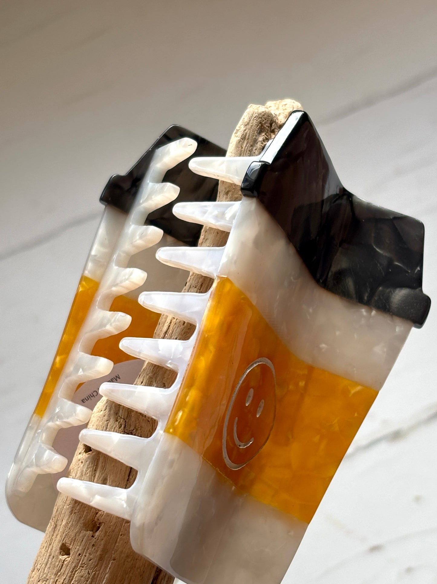 closeup shot of glossy marbled coffee cup hair claw with smiley face—fun, secure grip for quirky, caffeine-loving style