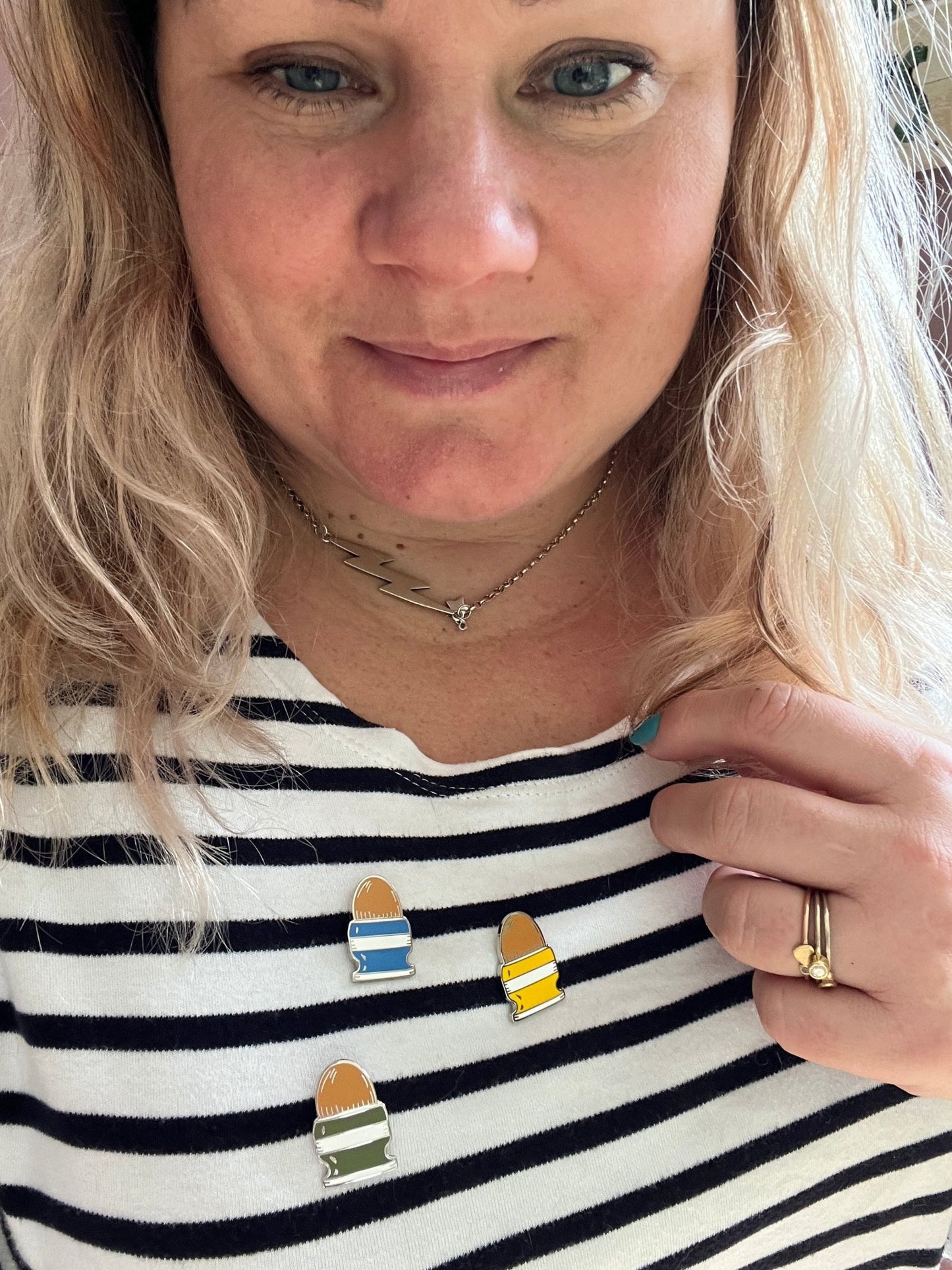 colorful easter egg in egg cup enamel pins displayed on classic striped top - festive spring lapel badges