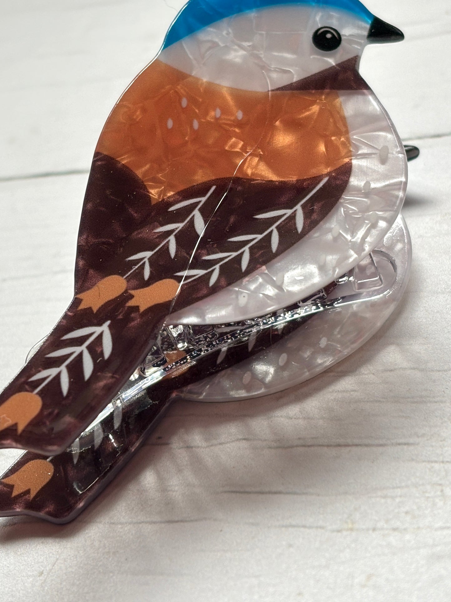 detail shot of the tail and claw mechanism of a colorful bird hair clip acrylic, floral pattern, unique hair accessory