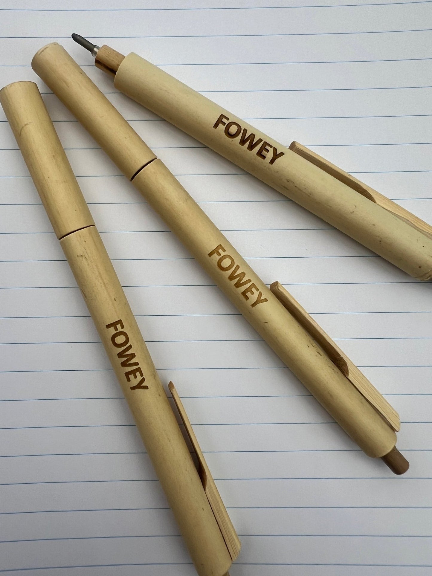closeup shot of engraved Fowey bamboo pens, natural wood grain ballpoint, sustainable Cornwall souvenir, eco writing tools