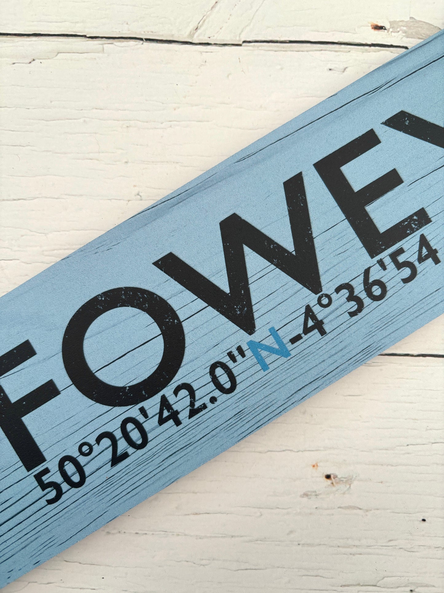 closeup shot of Fowey sign detail and coordinates on light blue distressed wooden arrow nautical decor, Cornwall souvenir