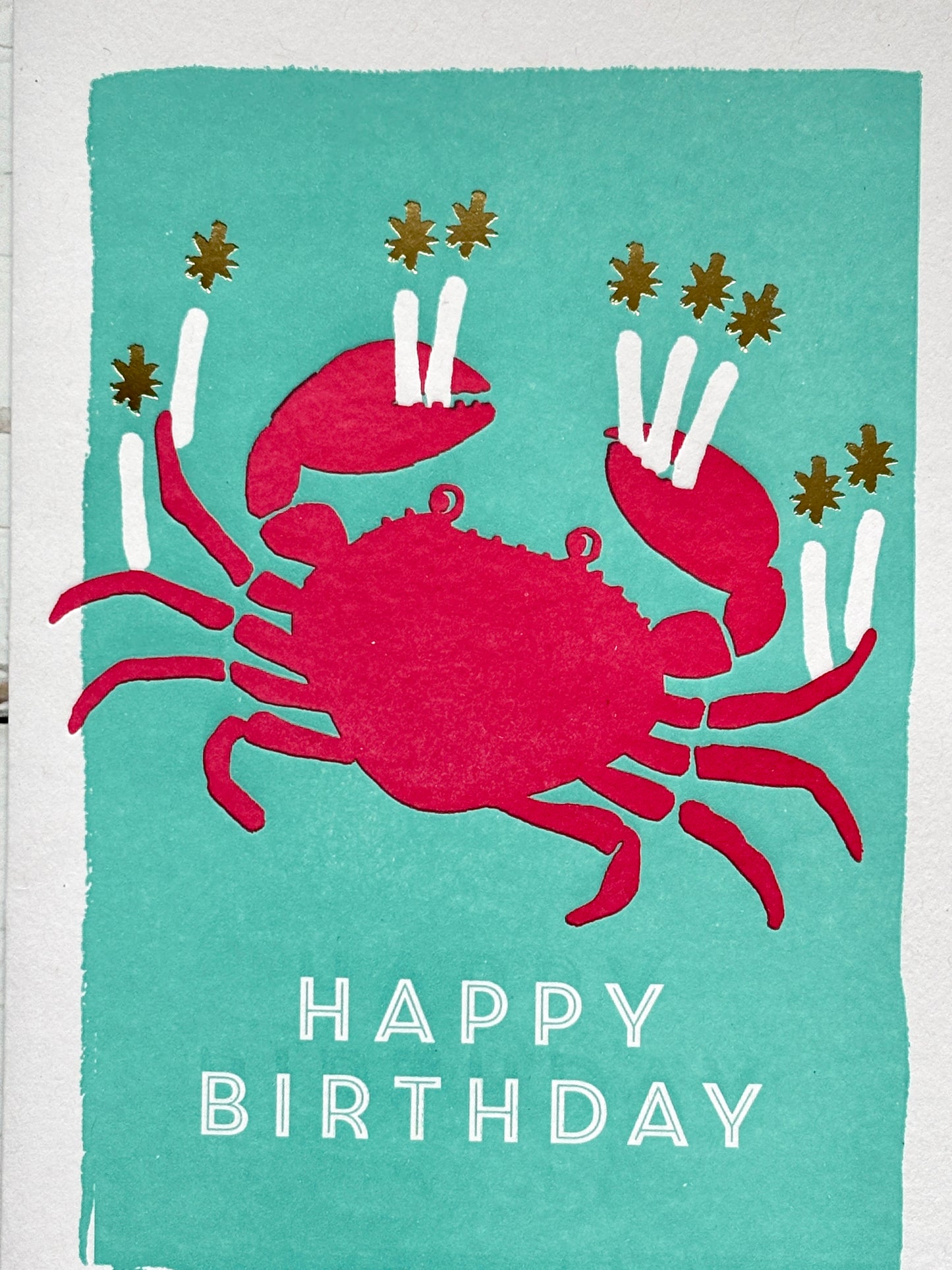 closeup shot of crab birthday card with gold sparkles on teal, festive ocean-themed design for beach lovers and summer celebrations