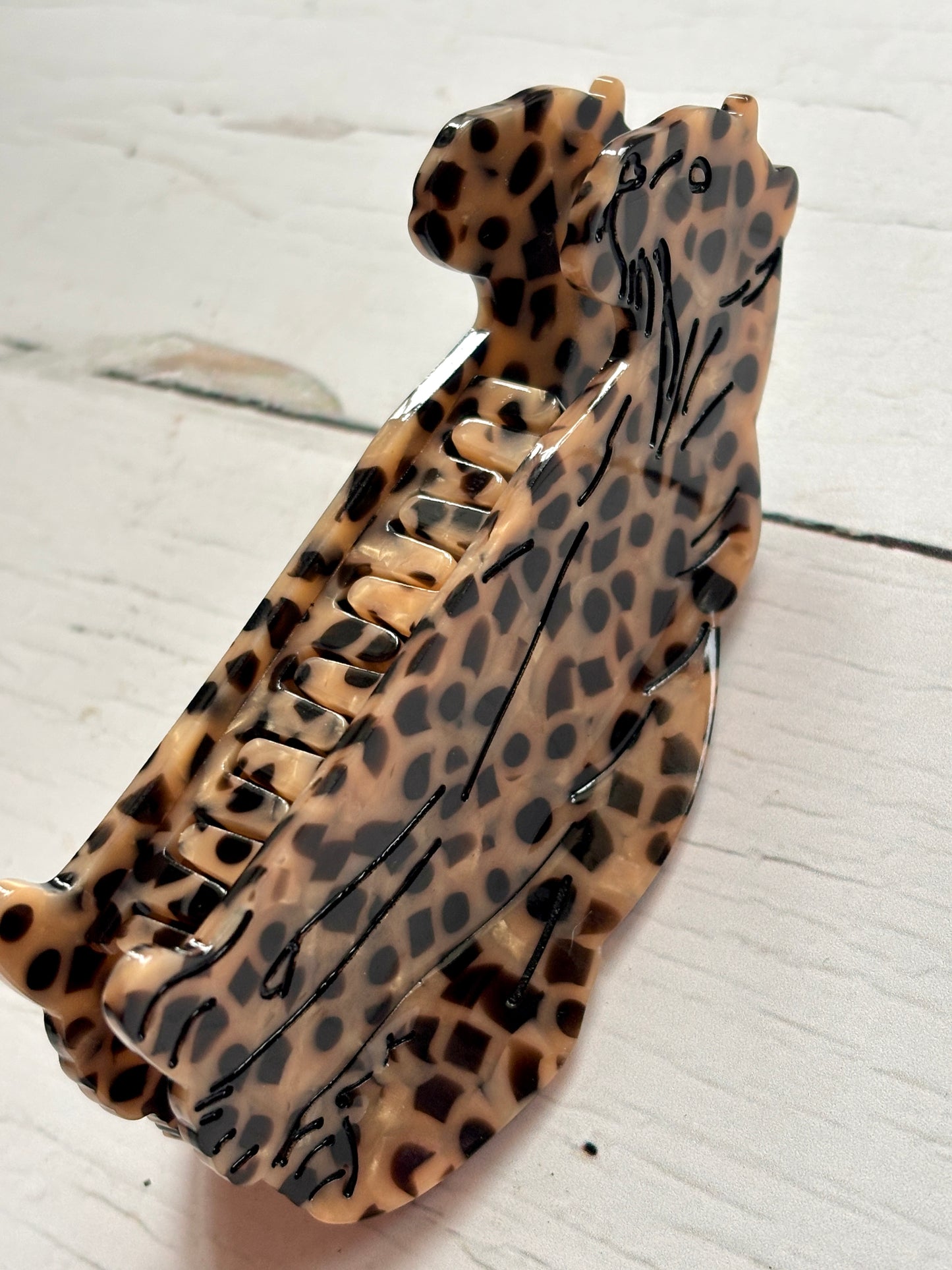 closeup shot of leopard-print hair claw—twin feline design, bold spots, and glossy finish for fierce, statement styling