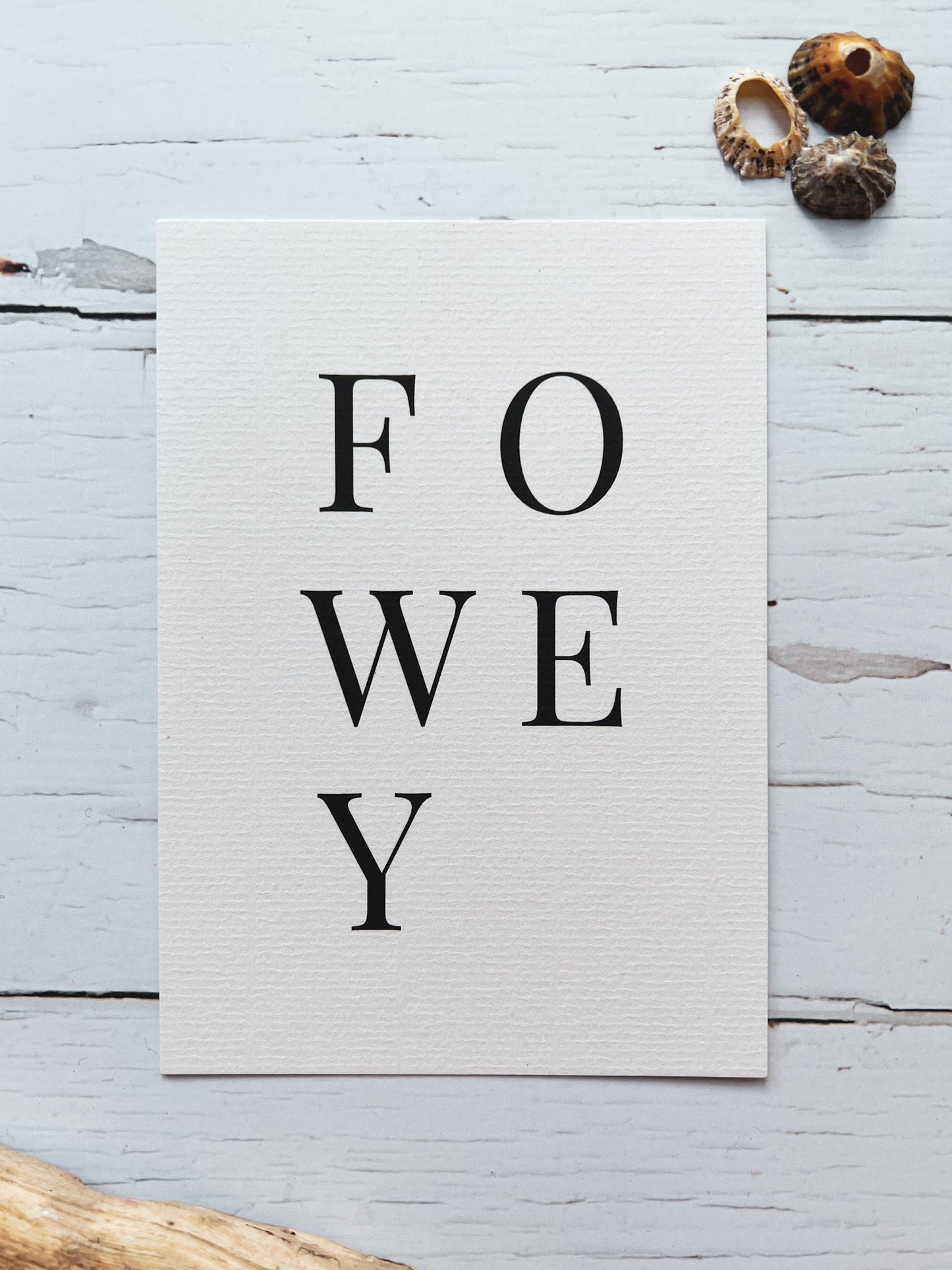 minimalist Fowey postcard with bold serif grid text, coastal driftwood, seashells, and nautical-inspired design