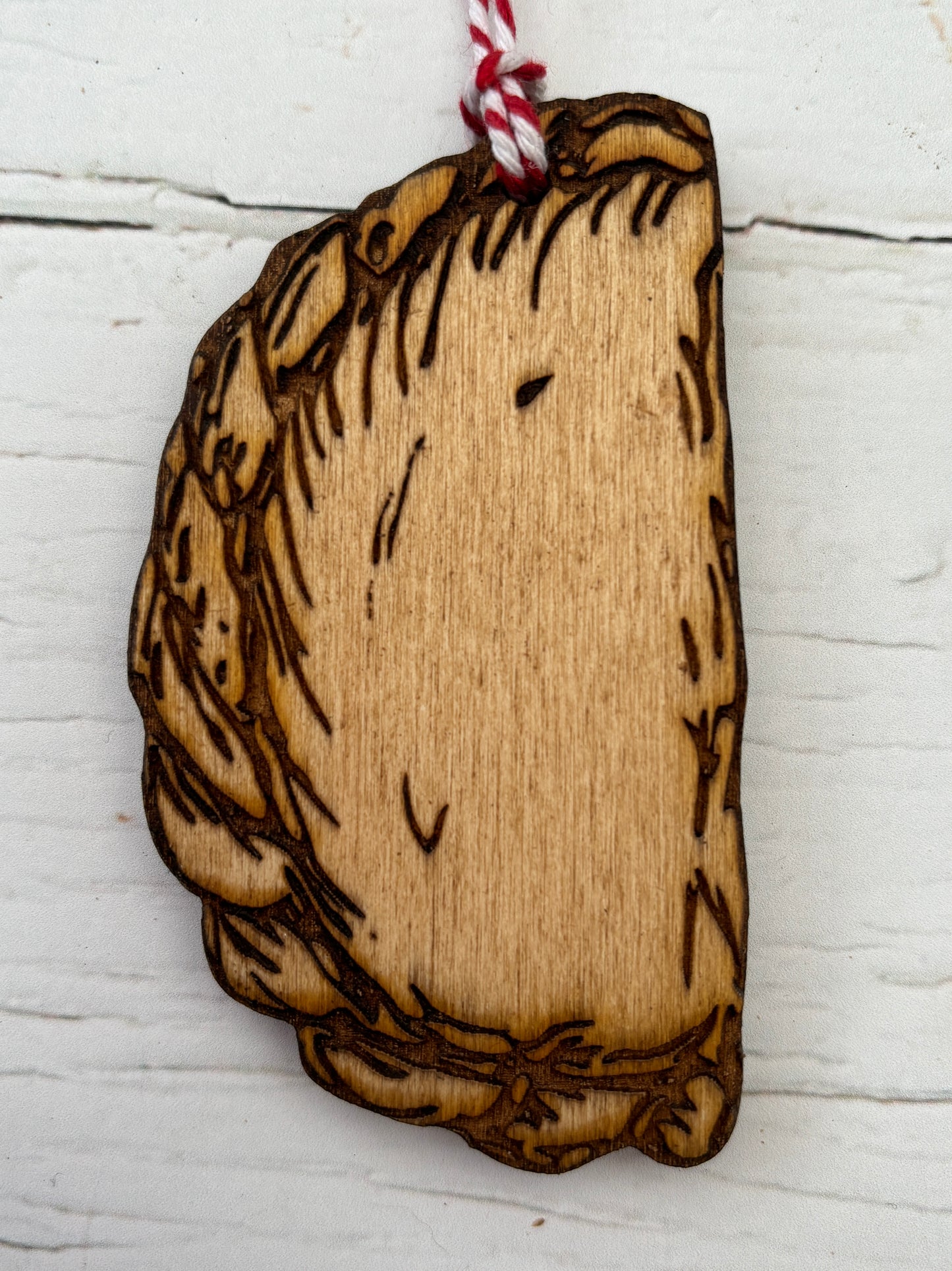 closeup shot of wooden Cornish pasty ornament laser-cut and burnt handmade wood decor with smiling face Cornwall souvenir