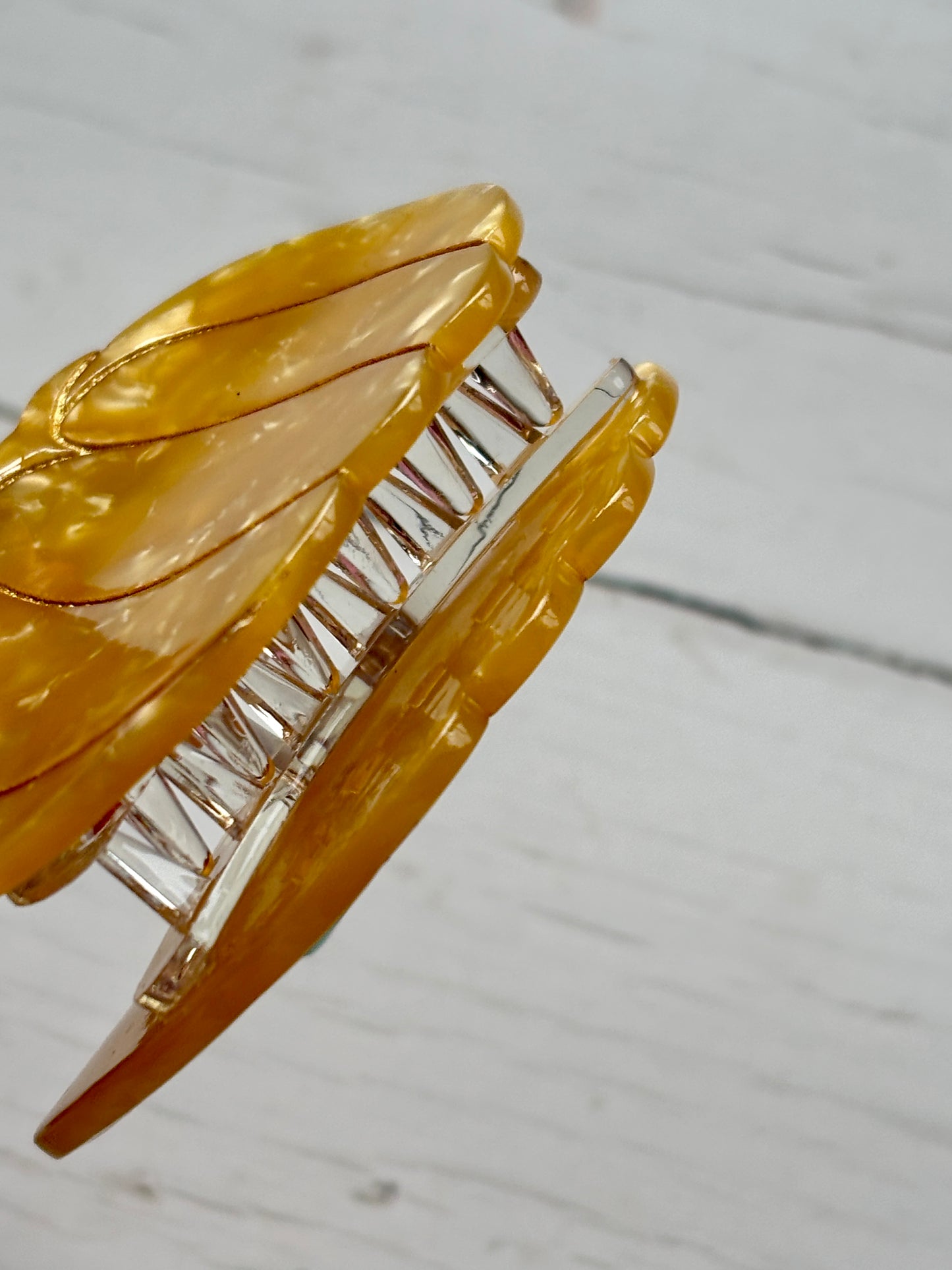 closeup shot of glossy yellow pumpkin hair claw—marbled texture, green stem, and firm grip for festive fall looks