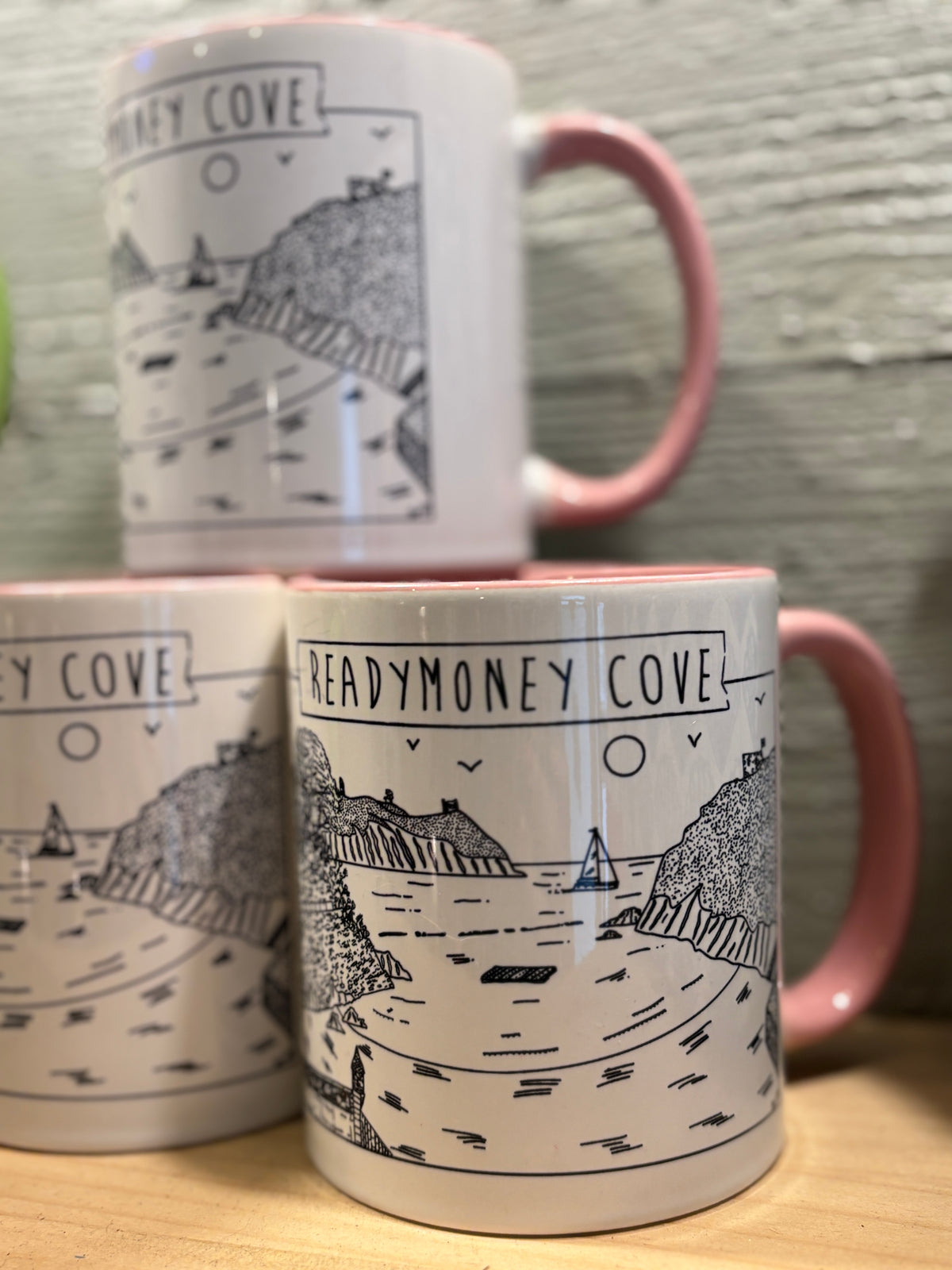 a mug with a black & white illustration of readymoney cove, pale pink handle and interior