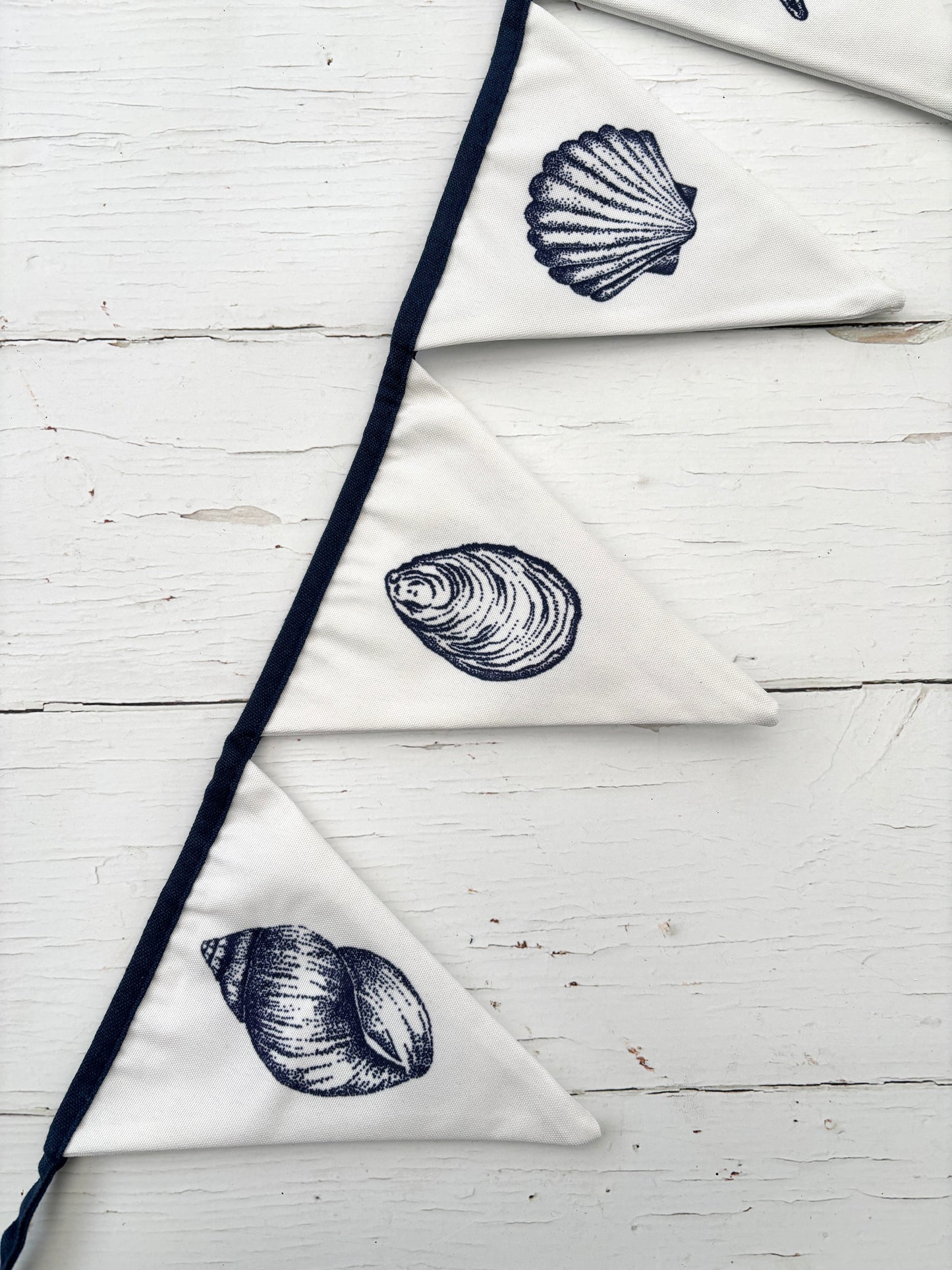 closeup shot of white cotton bunting with navy seashell illustrations—nautical garland for coastal decor and beach events