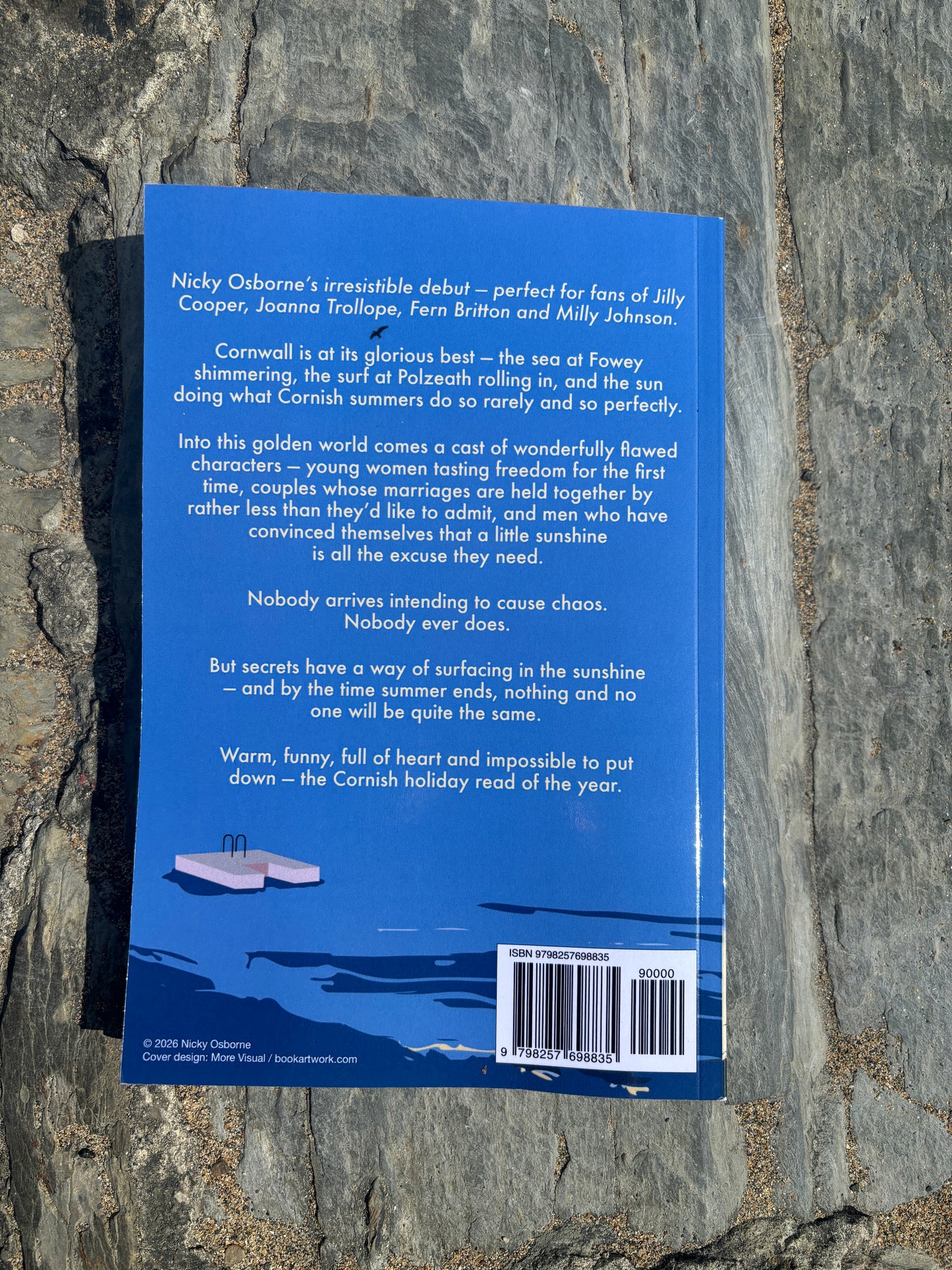 Blue book cover with text and a barcode on a stone surface