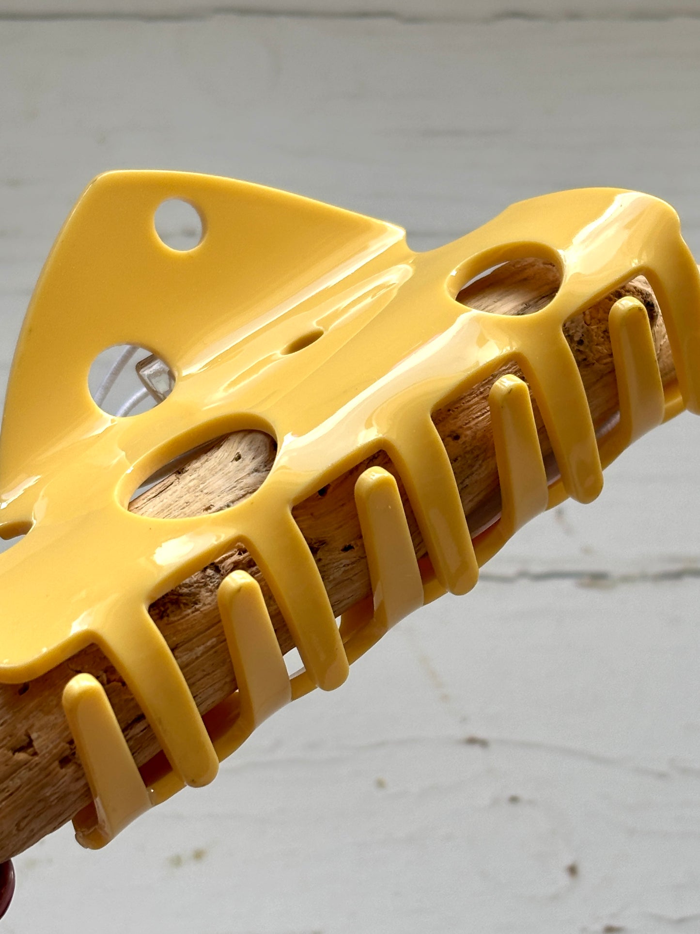 closeup shot on the yellow plastic teeth of a novelty cheese slice hair claw funky hair accessory with a Swiss cheese design