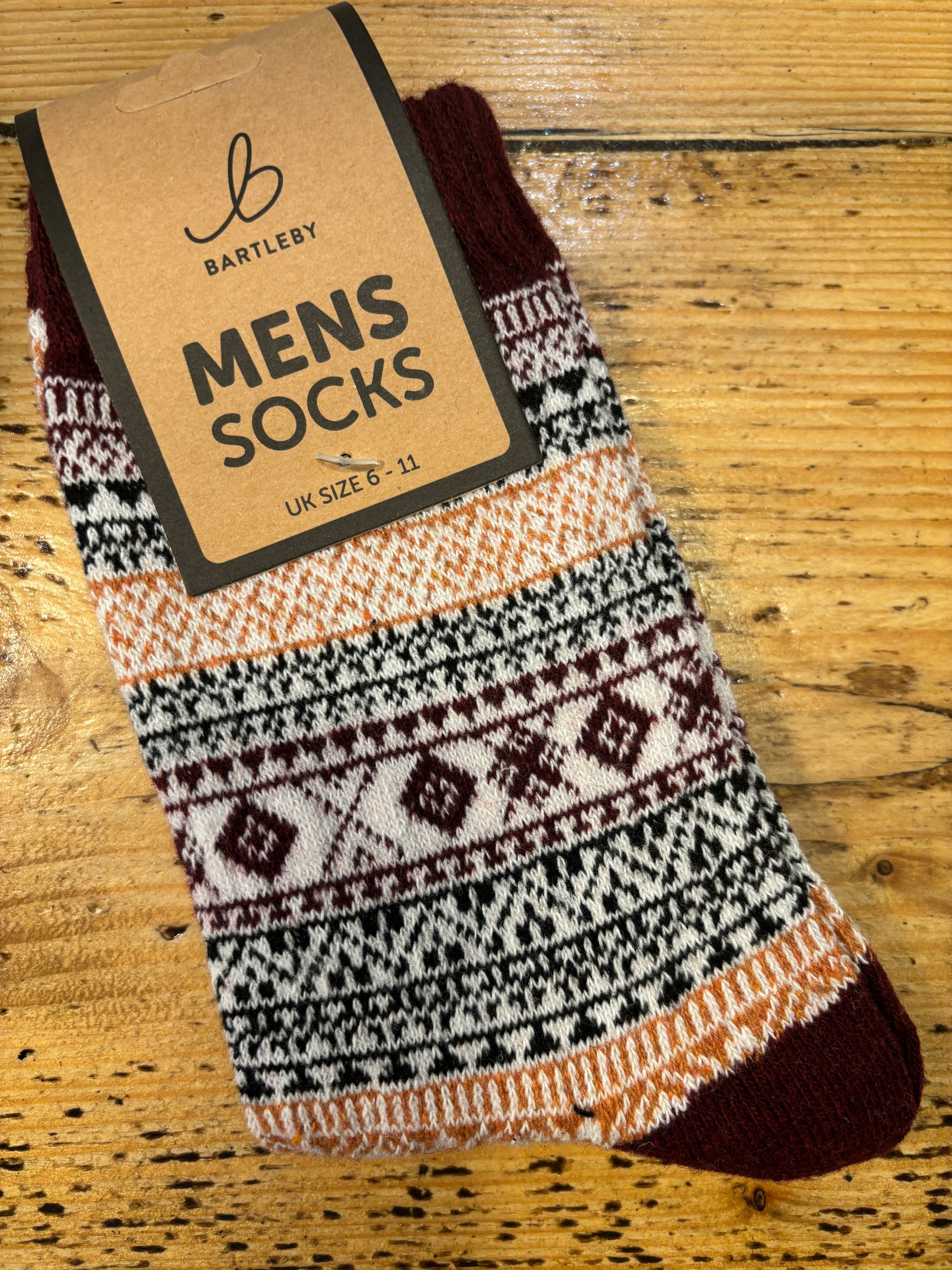 Colorful patterned Bartleby Men’s socks in brown, white, and orange tones on wooden surface