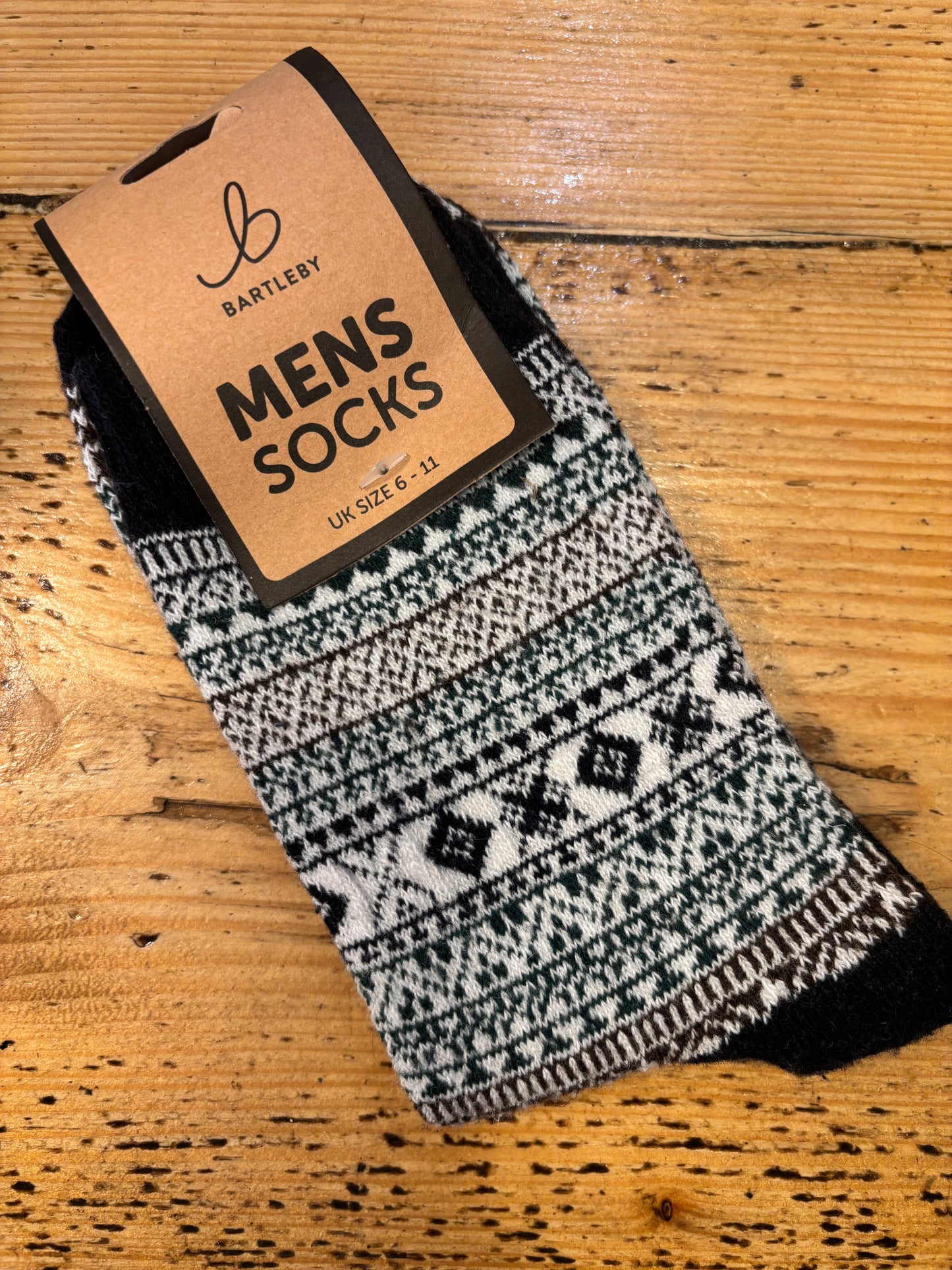 Colorful patterned Bartleby Men’s socks in burgundy, white, and orange tones on wooden surface