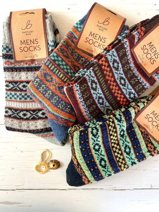 Colorful patterned Bartleby Men’s socks in various designs on a white wooden surface, decorated with seashells