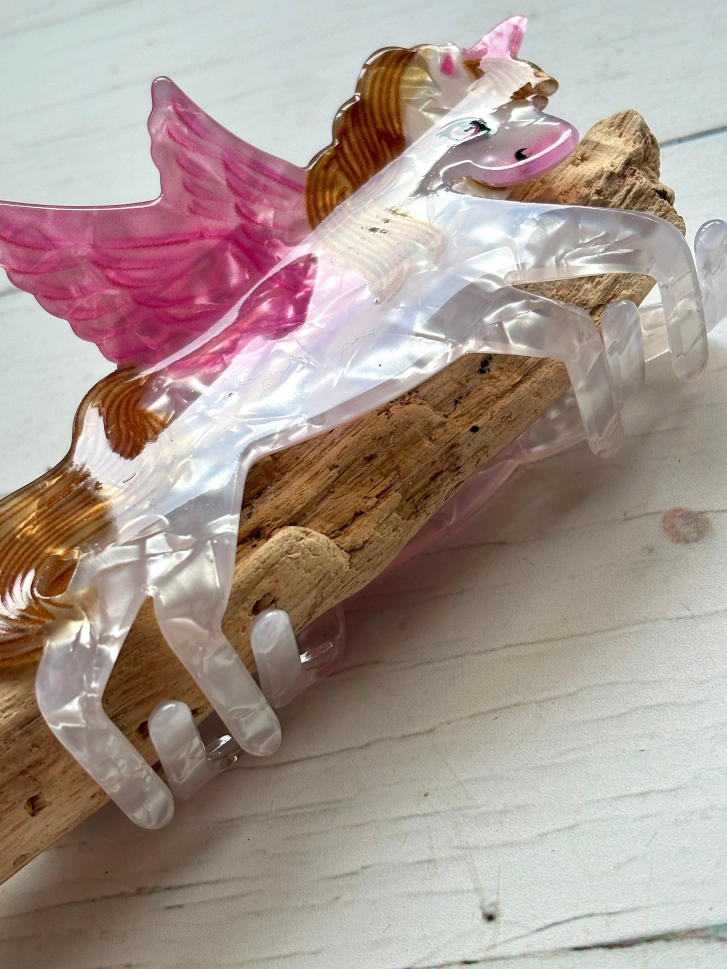 closeup shot on a marbled pink and white pearlescent unicorn hair claw clip funky Pegasus novelty hair accessory or cute statement hair decor