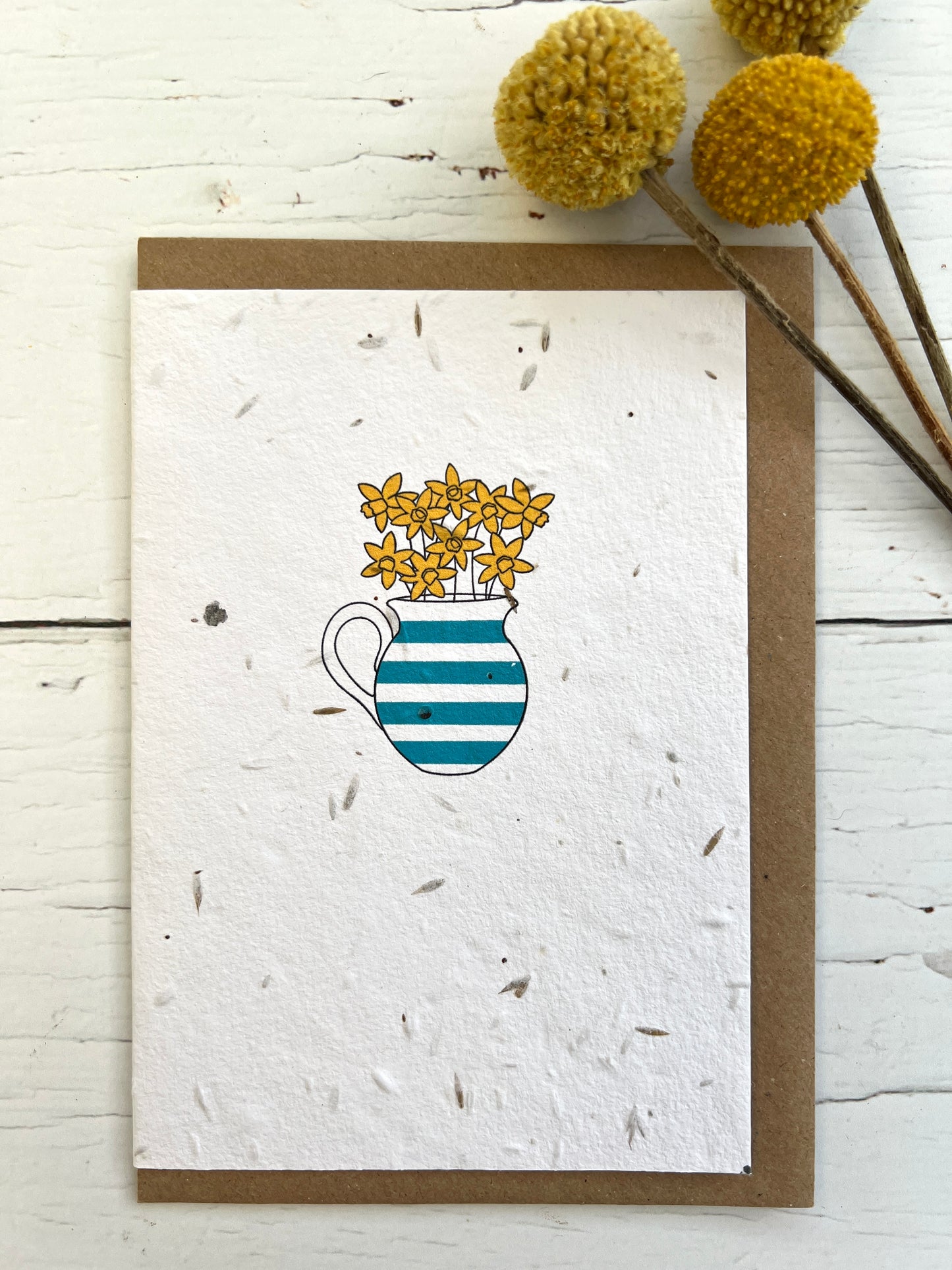 a natural coloured greetings card embedded with meadow seeds. The image on the card is a blue & white striped just of daffodils