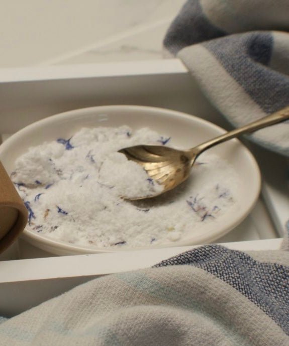bath bomb powder in dish with brass spoon, coastal linen towel, relaxing spa bath product styling