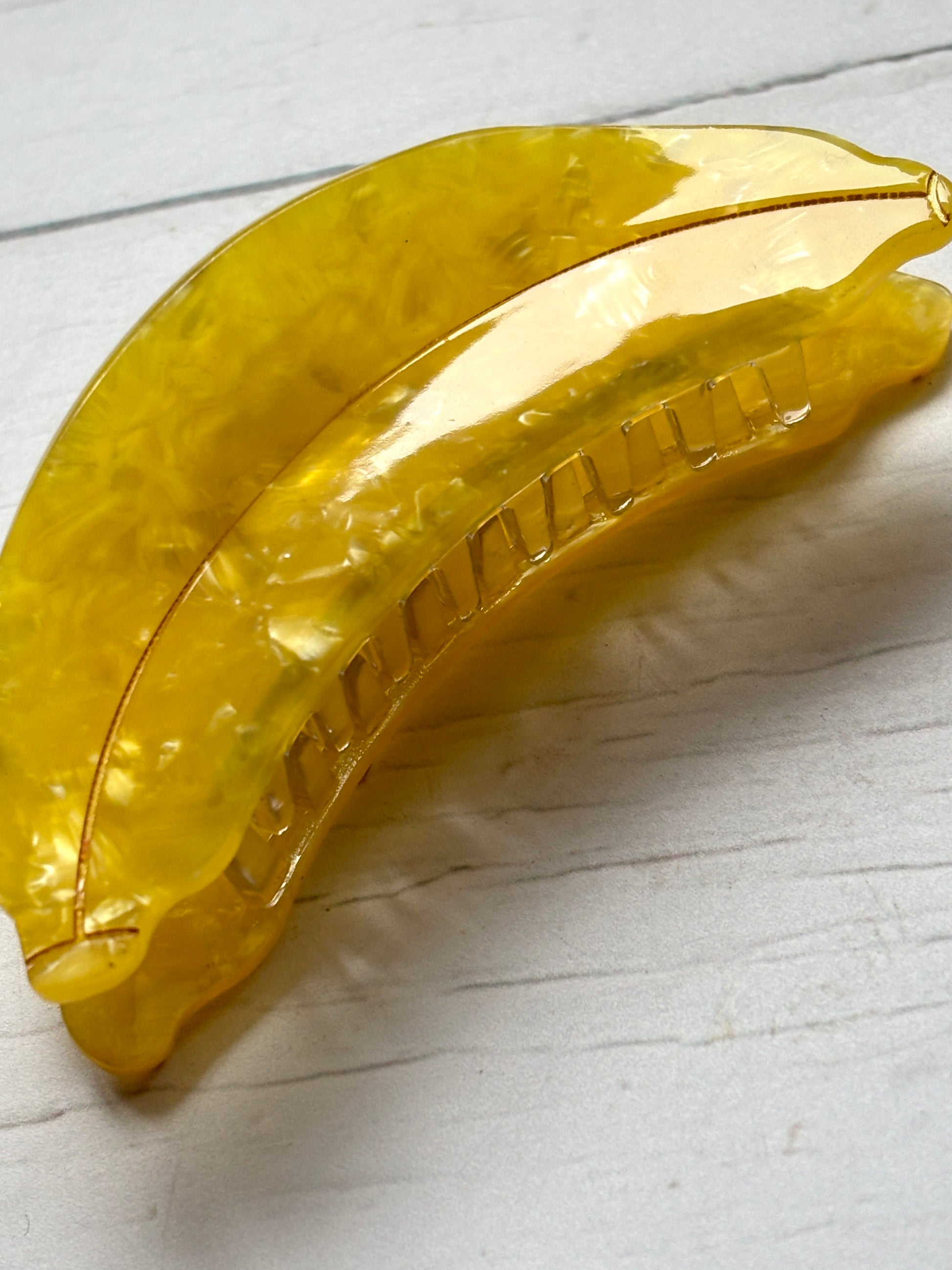 closeup shot of the bright yellow marbled acrylic banana hair claw clip, showing the strong grip teeth mechanism fun hair accessory