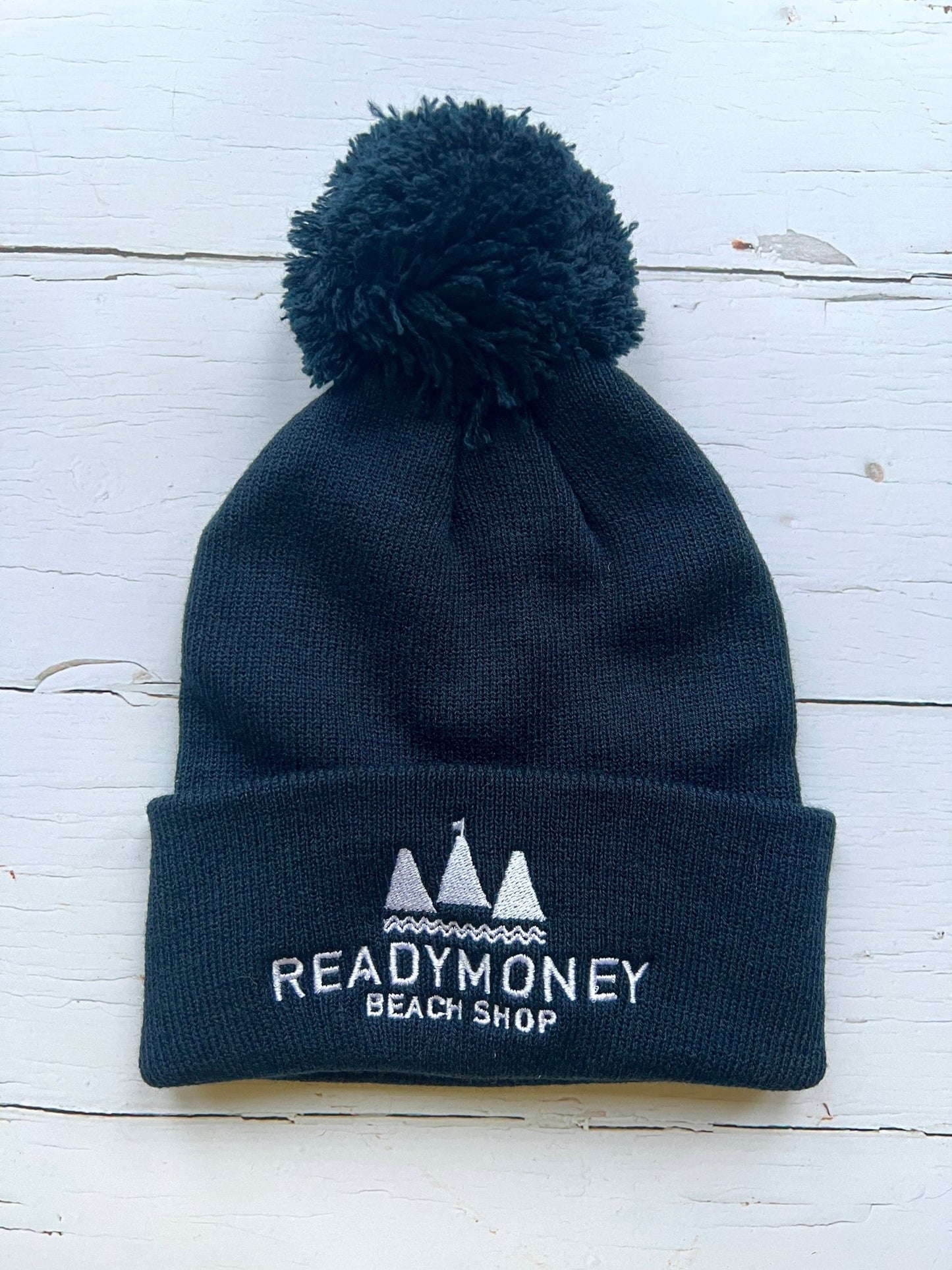 navy blue kids’ beanie with pom-pom, soft knit, and embroidered beach shop logo—warm, coastal, and stylish