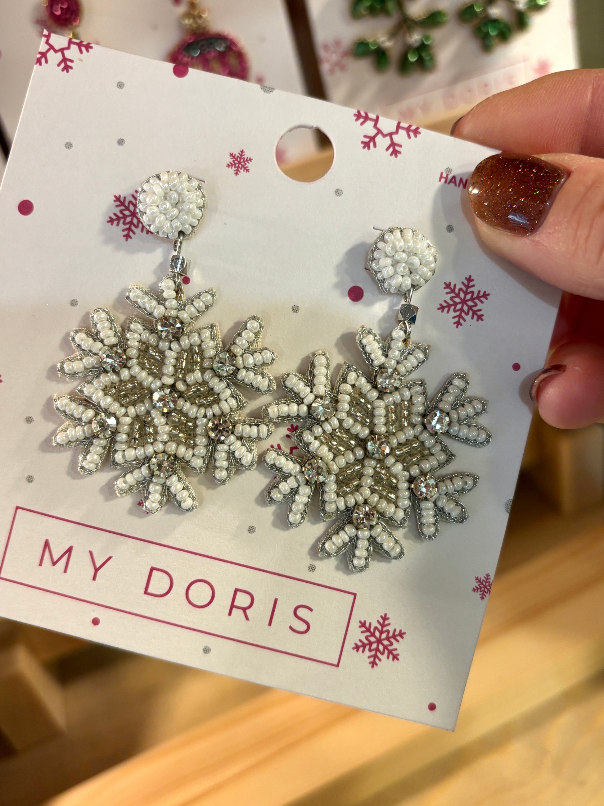 a pair of white and silver beaded christmas earrings shaped like snowflakes