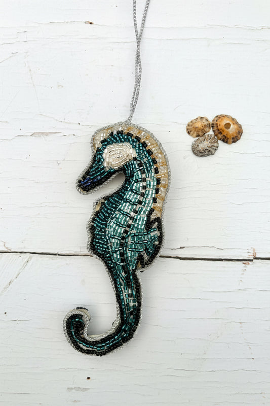 A beaded seahorse luxury hanging Christmas decoration with a festive message background.
