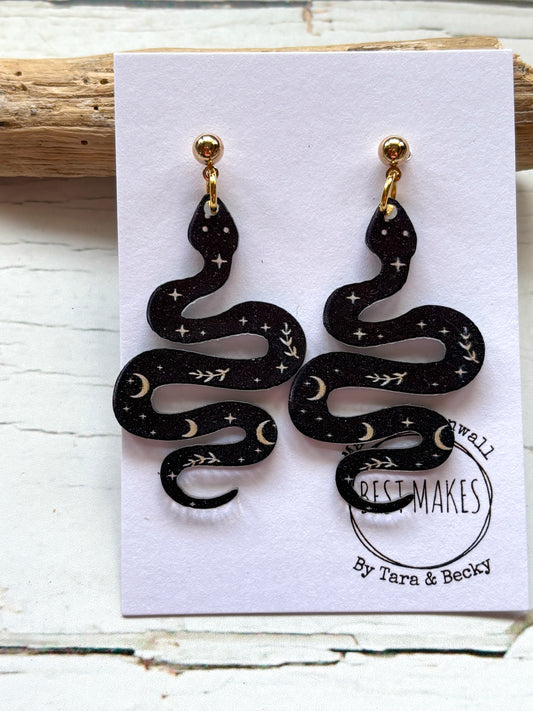 black polymer resin snake earrings witchy celestial jewelry with moon and star print gothic serpent fashion accessories