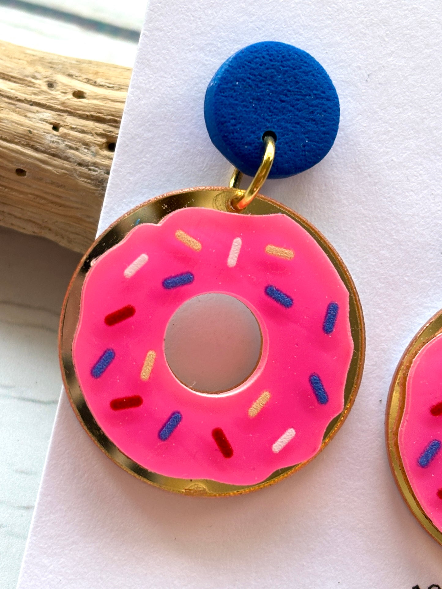 closeup shot of hot pink donut earrings with sprinkles with royal blue polymer resin stud novelty foodie jewelry