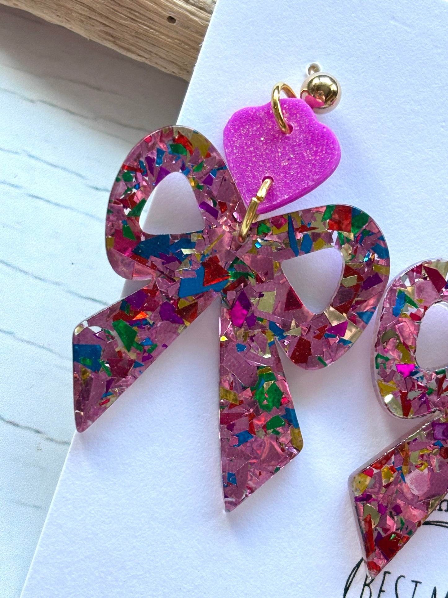 closeup shot of sparkle bow earring fuchsia heart stud detail above the glitter acrylic bow handmade statement party jewelry accessory
