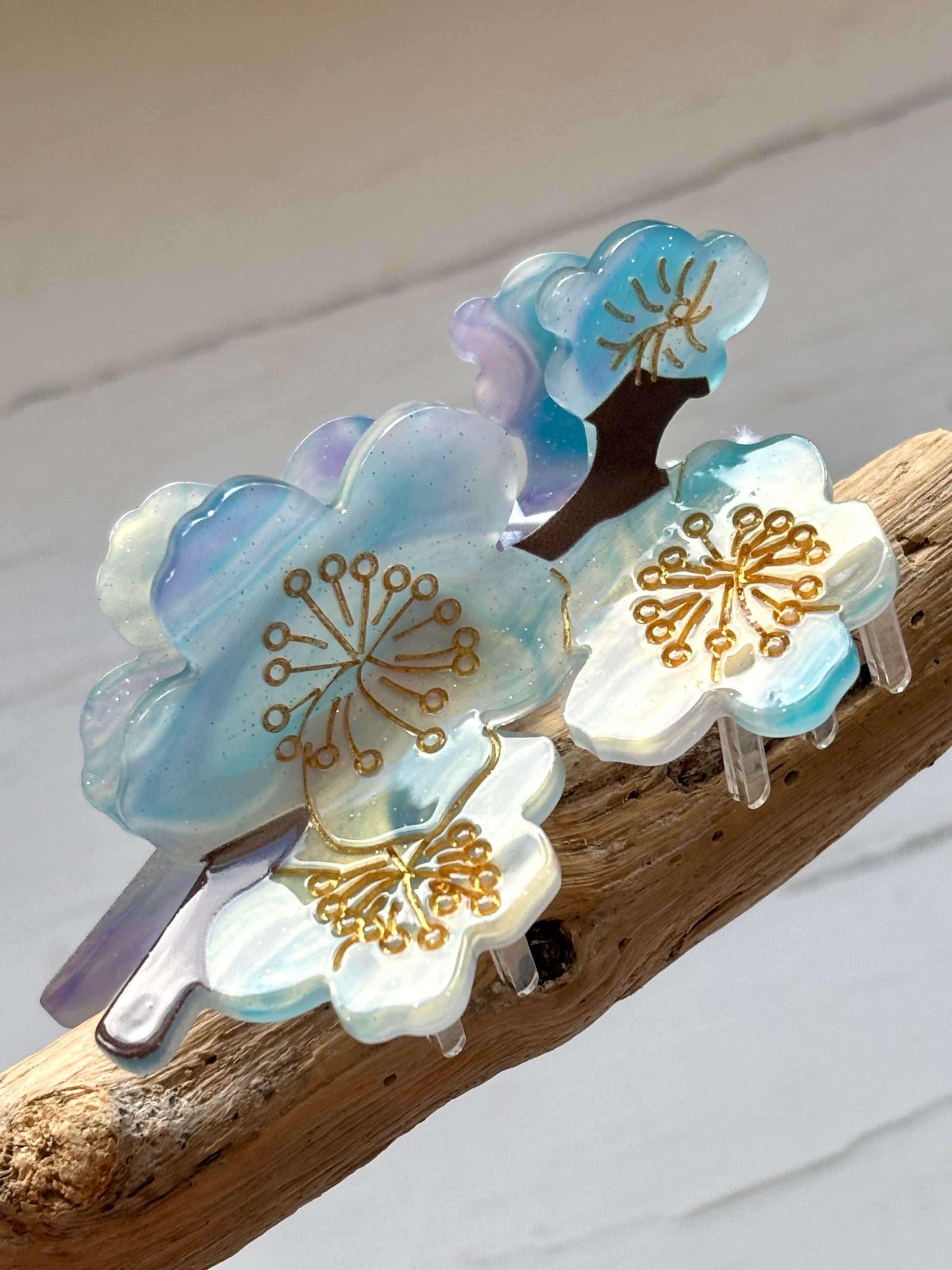 closeup shot of blue blossom hair claw clip with gold flower details, iridescent acrylic accessory for stylish spring hairstyles