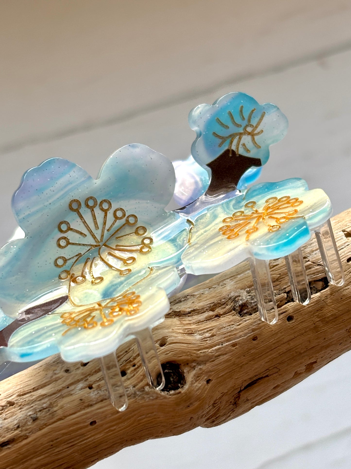 blue blossom hair claw clip with gold floral details, pearlescent finish, and elegant spring-inspired hair accessory design