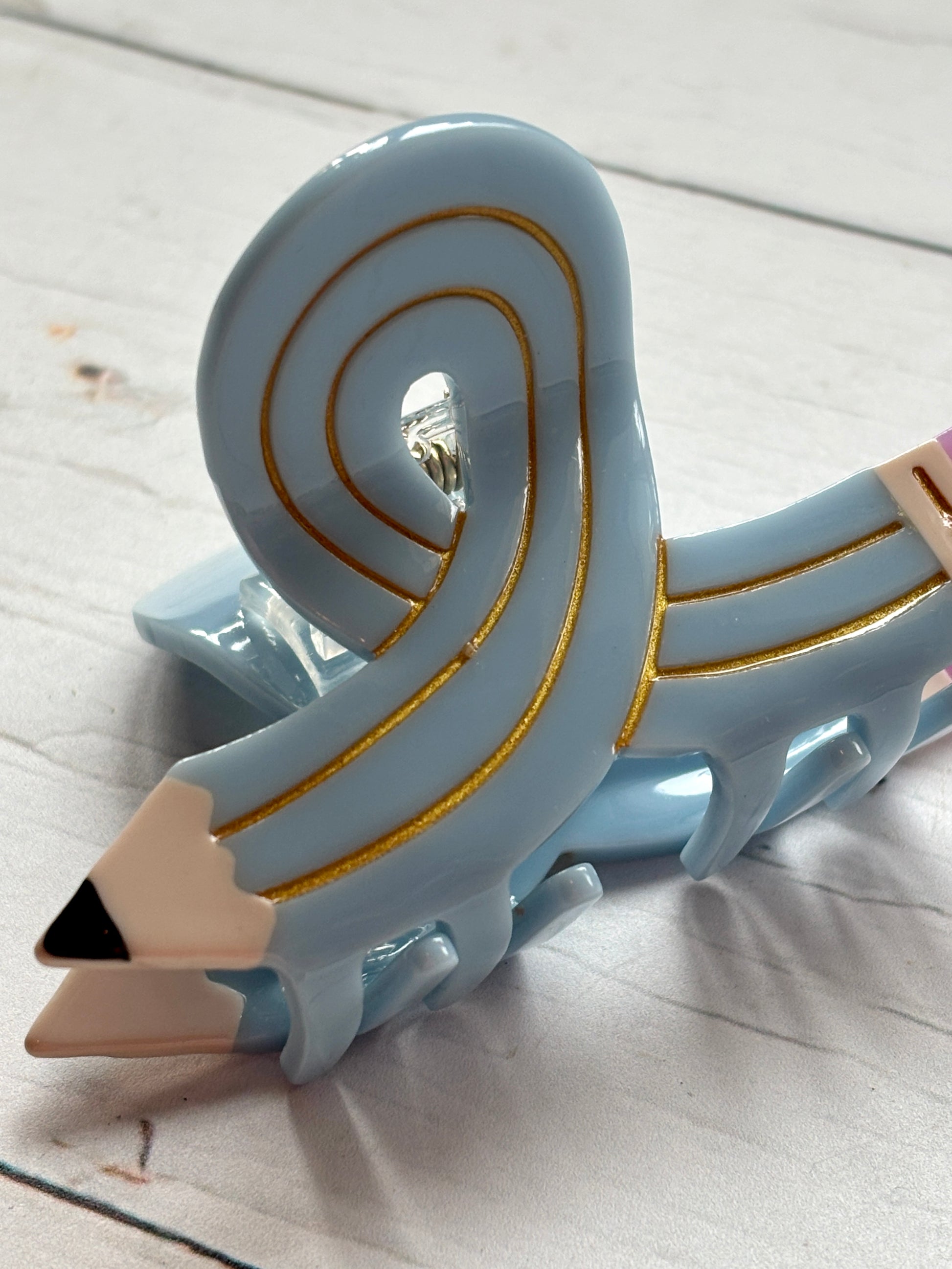 closeup shot of the light blue curled pencil hair claw clip, showing the pointed tip and gold line detail novelty school accessory