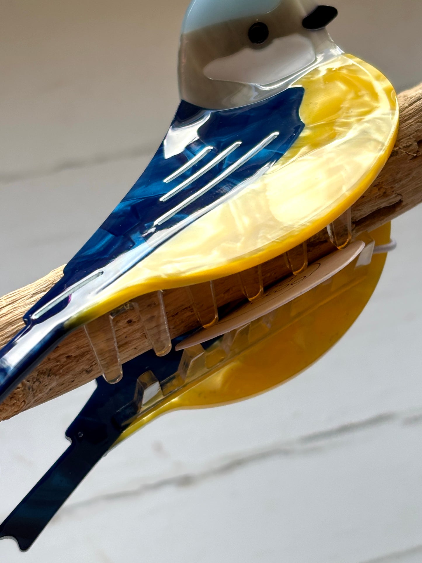 closeup shot of blue tit bird hair claw – glossy ceramic clip with vivid plumage, secure grip, and artistic hand-painted detail
