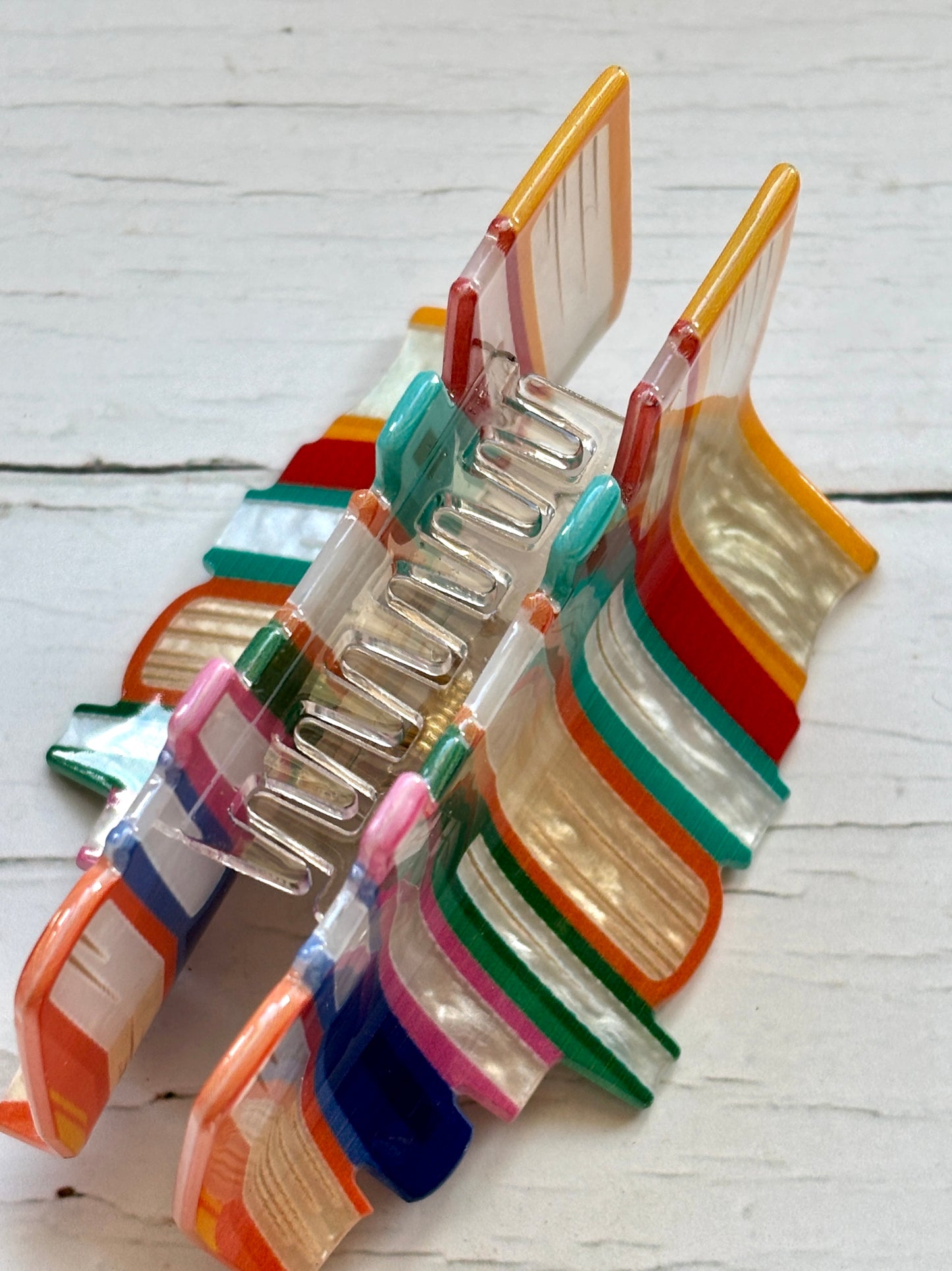 closeup shot on a colorful marbled acrylic hair claw clip shaped like a stack of books unique novelty accessory for book lovers and teachers