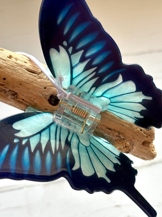 closeup showing the clear plastic mechanism and vibrant blue gradient wings of a large butterfly hair claw trendy statement accessory
