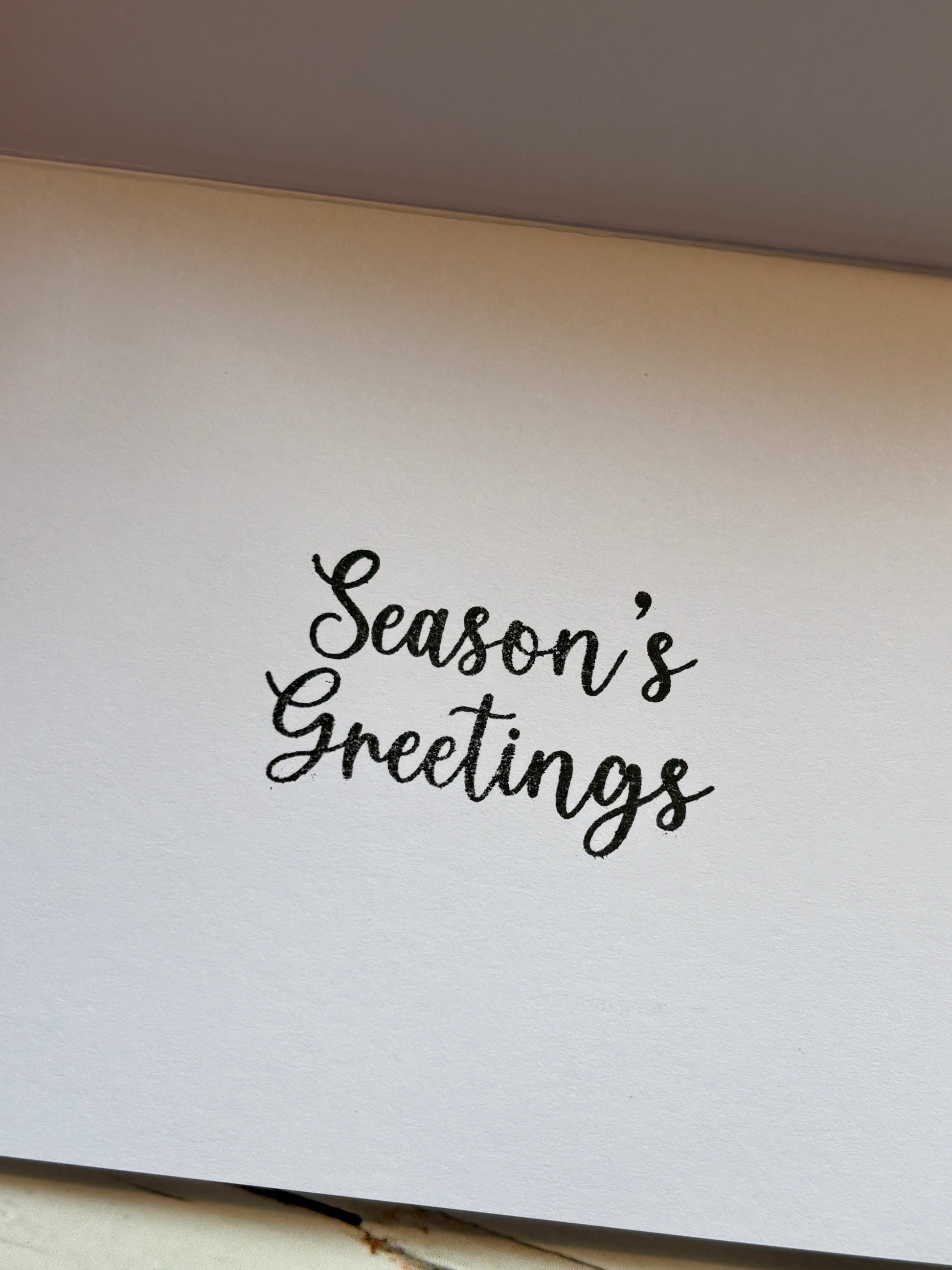 inside of a Christmas card featuring "Season's Greetings" in black script font holiday messages, generic greeting card text
