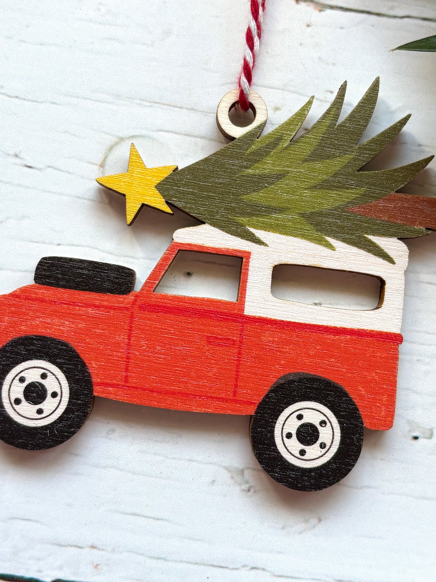 closeup shot of wooden red and white Land Rover decor off-road vehicle Christmas tree and star on top retro vehicle holiday decor