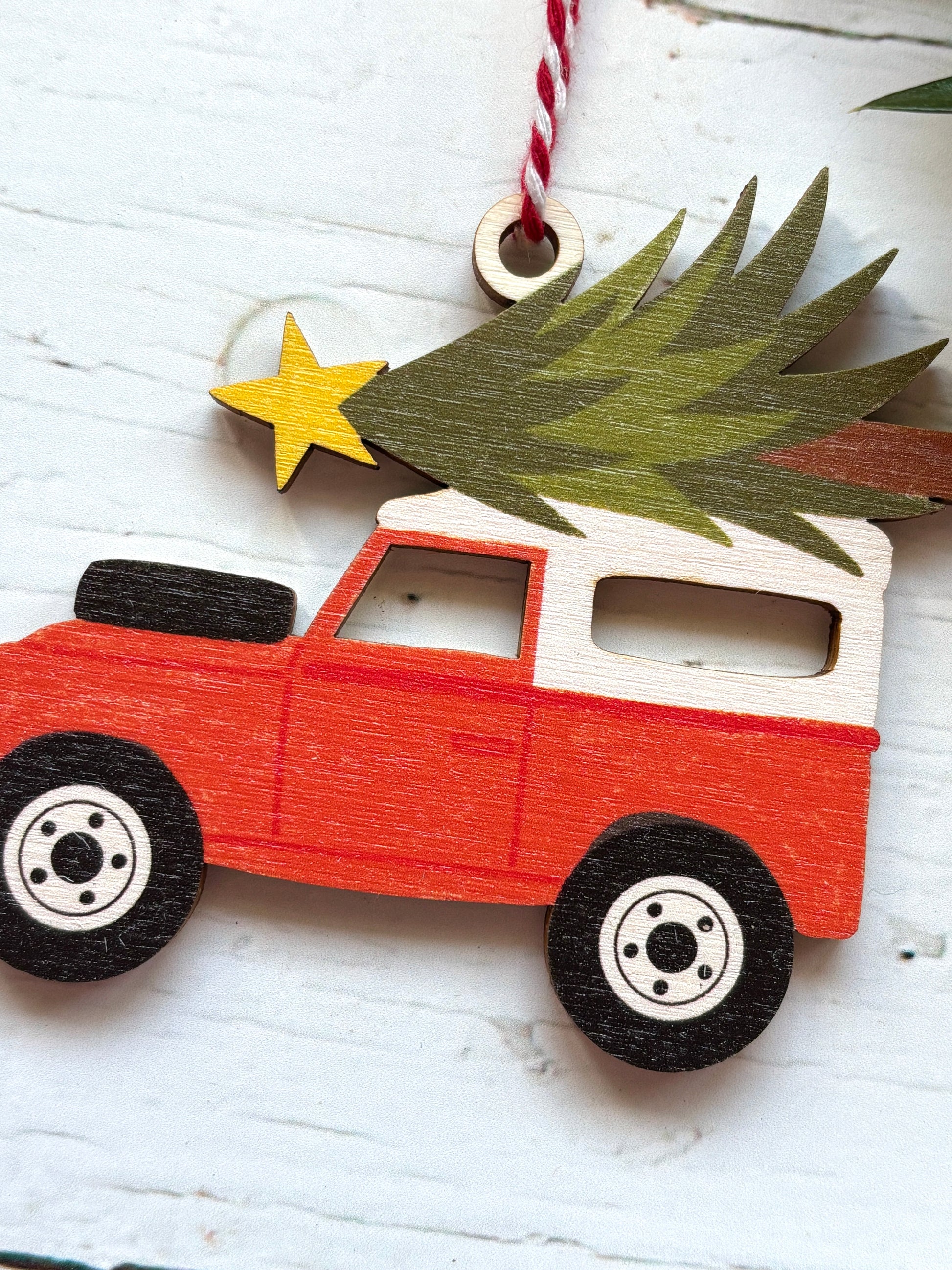 closeup shot of wooden red and white Land Rover decor off-road vehicle Christmas tree and star on top retro vehicle holiday decor