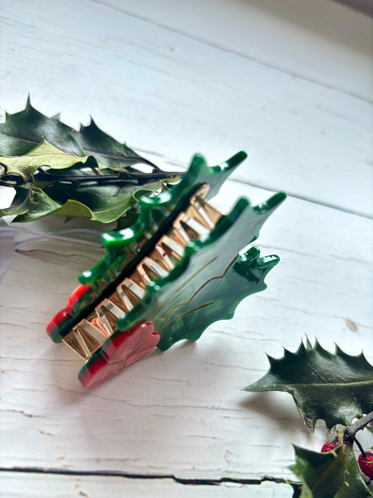 closeup shot of Christmas holly hair claw shiny green clip with red berries and gold wire detail festive holiday hair accessory
