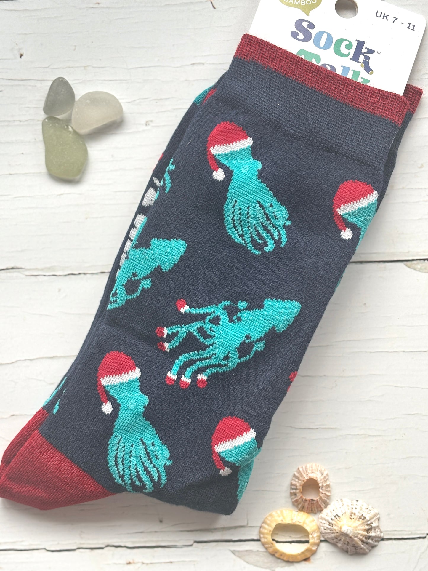blue novelty bamboo socks patterned with teal octopuses/squids each sea creature wears a red Santa hat fun coastal holiday gift
