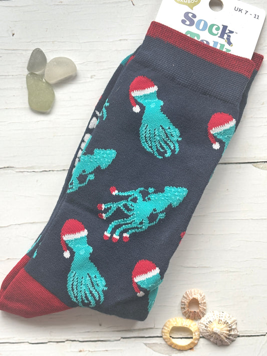 blue novelty bamboo socks patterned with teal octopuses/squids each sea creature wears a red Santa hat fun coastal holiday gift