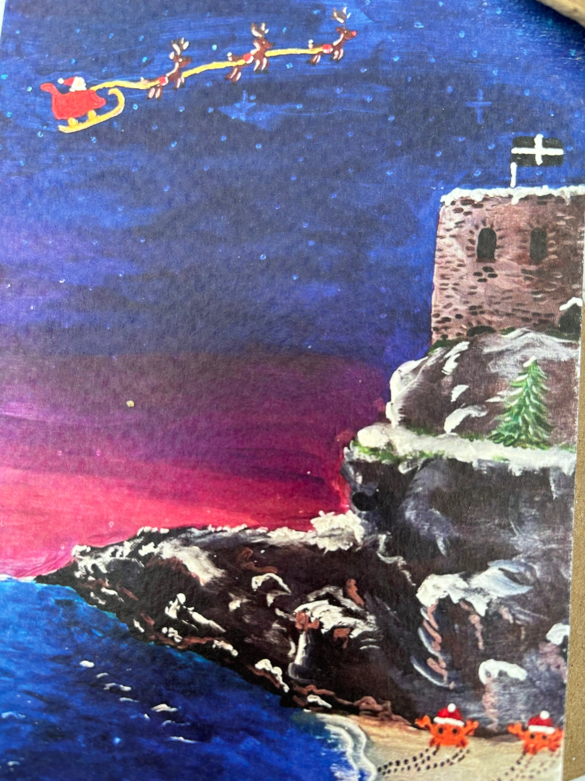 closeup shot of St Catherine's Castle Christmas card Santa's sleigh, Cornish flag, snowy cliff, festive seaside art, holiday greeting