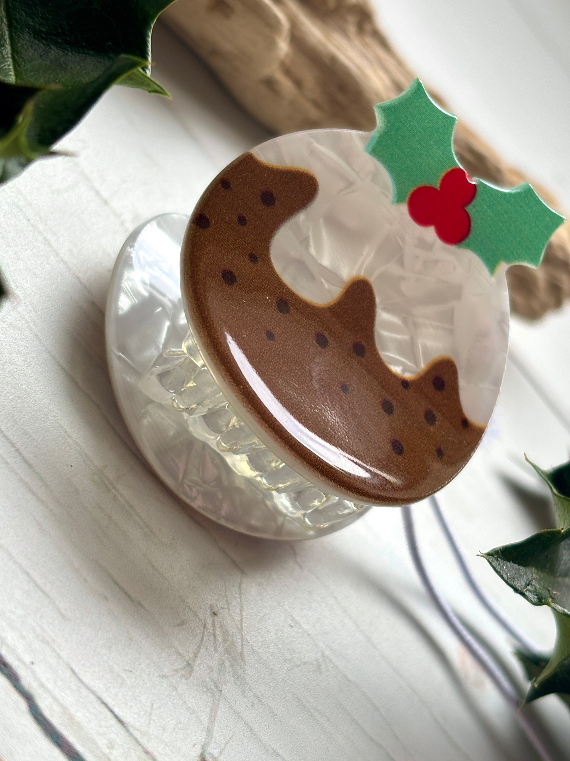 closeup shot of Christmas pudding hair claw brown dessert clip with white icing and holly leaf detail festive novelty hair accessory