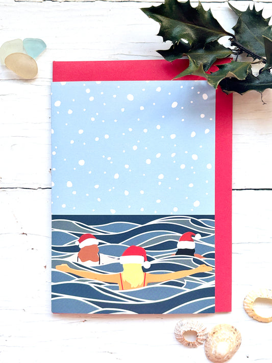 Christmas swim friends card, three swimmers in Santa hats, snowy winter ocean scene, festive cold water swimming