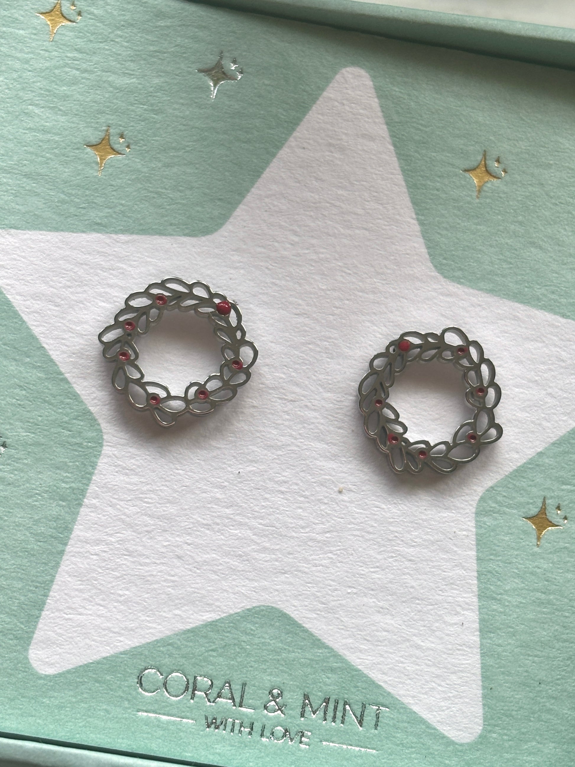 Christmas Wreath stud earrings—elegant silver loops with red accents on festive card, ideal for holiday jewelry and seasonal gifting