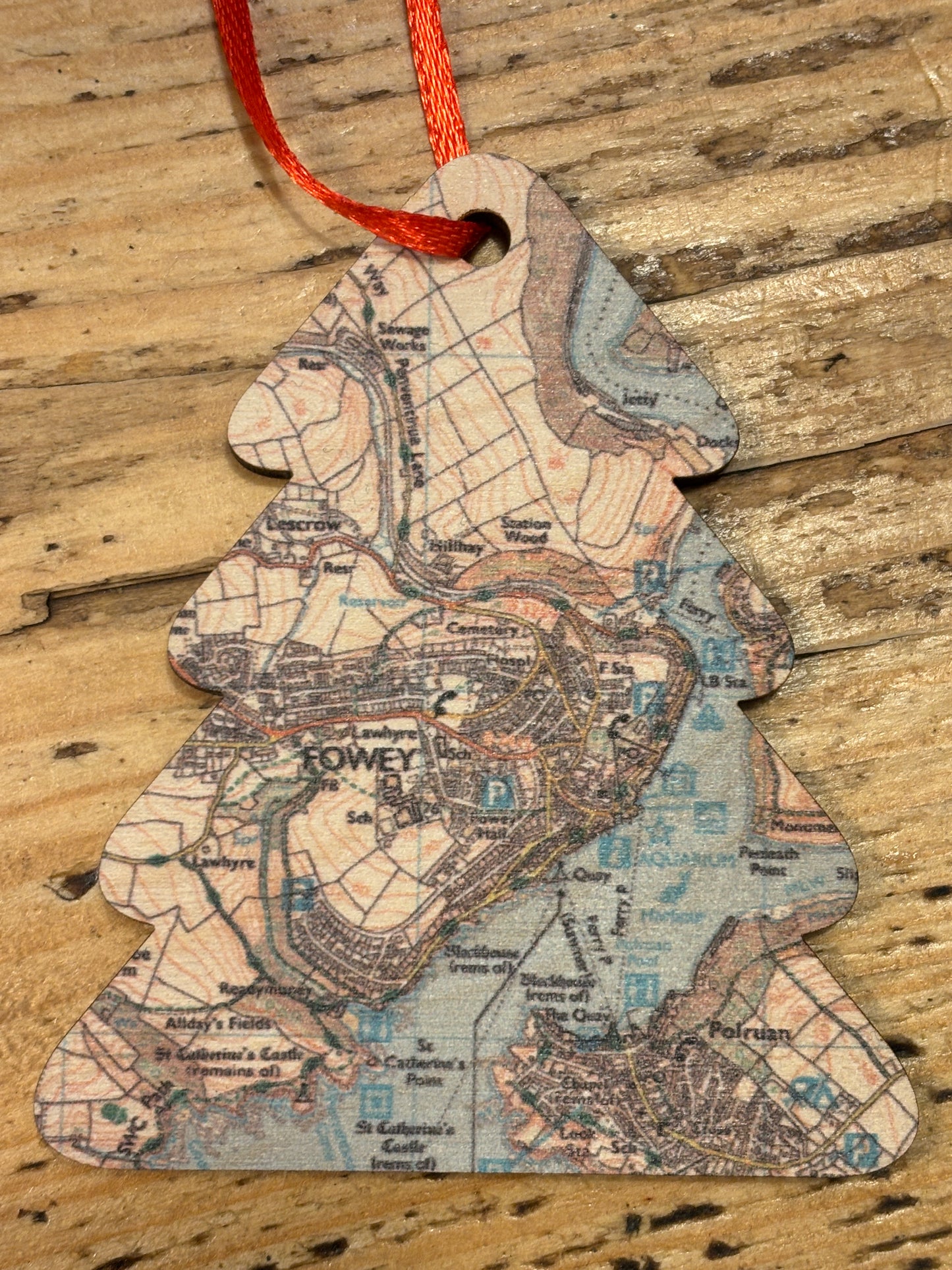 Map patterned christmas decoration with a red string on a wooden surface